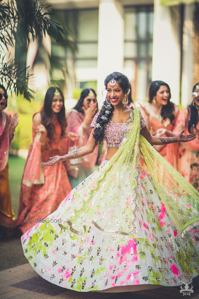 Photo of Bride twirling in unique mehendi lehenga with bridesmaids