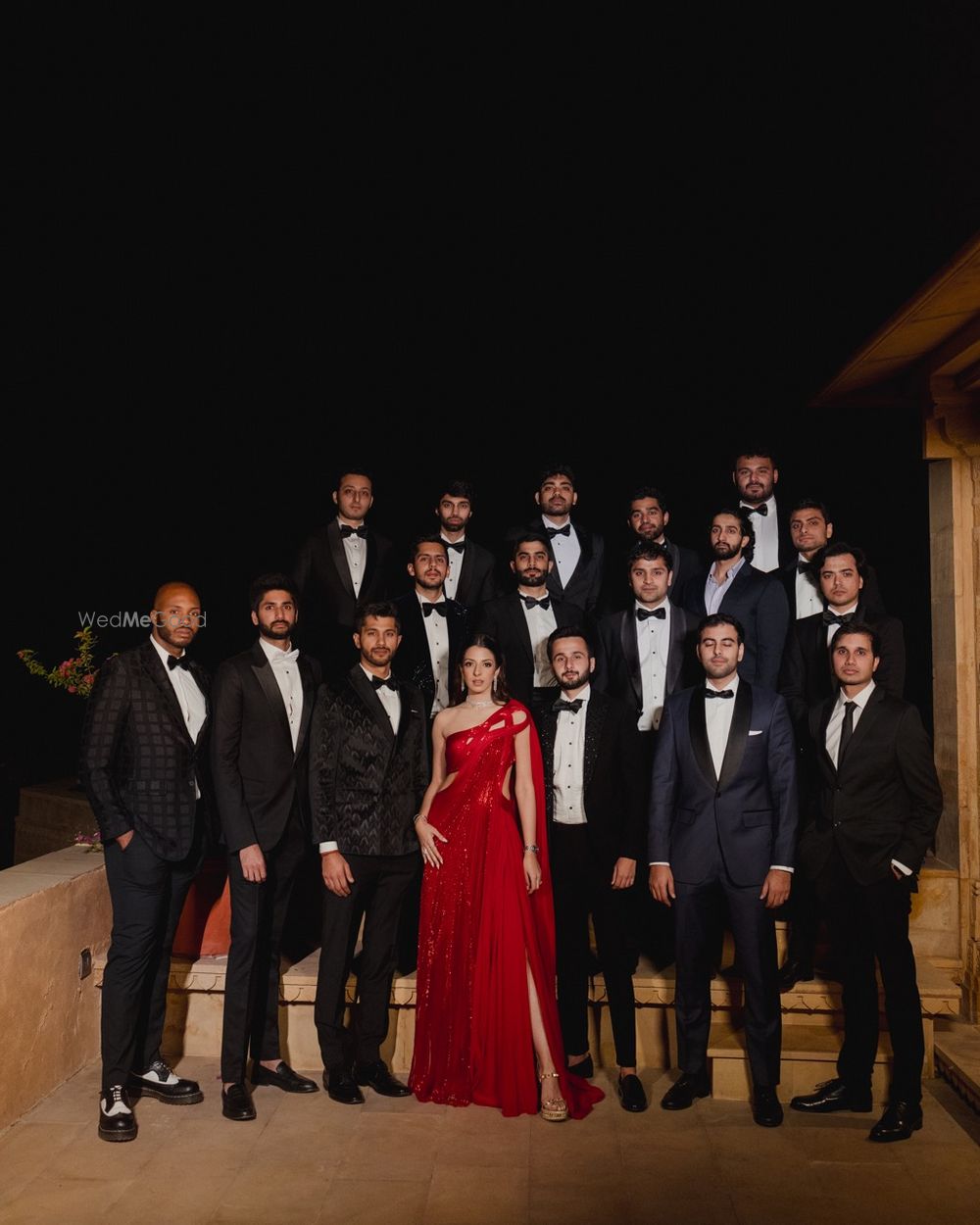 Photo of Group shot of the bride and the groom with all the groomsmen in black tuxedos