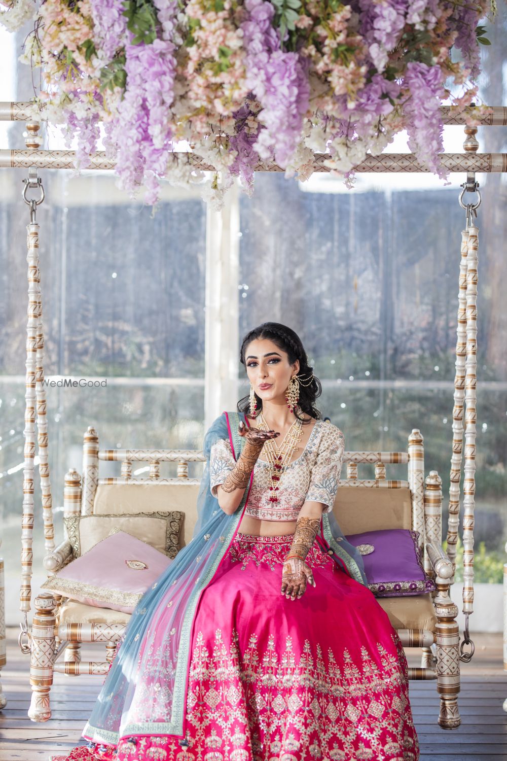 Photo of Bride wearing a pink and white lehenga with a blue dupatta on mehndi.