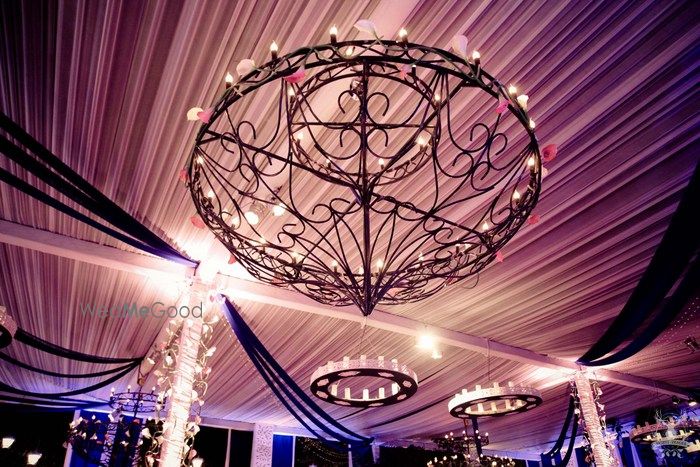 Photo of glamorous ceiling decor with wrought iron chandeliers and candles