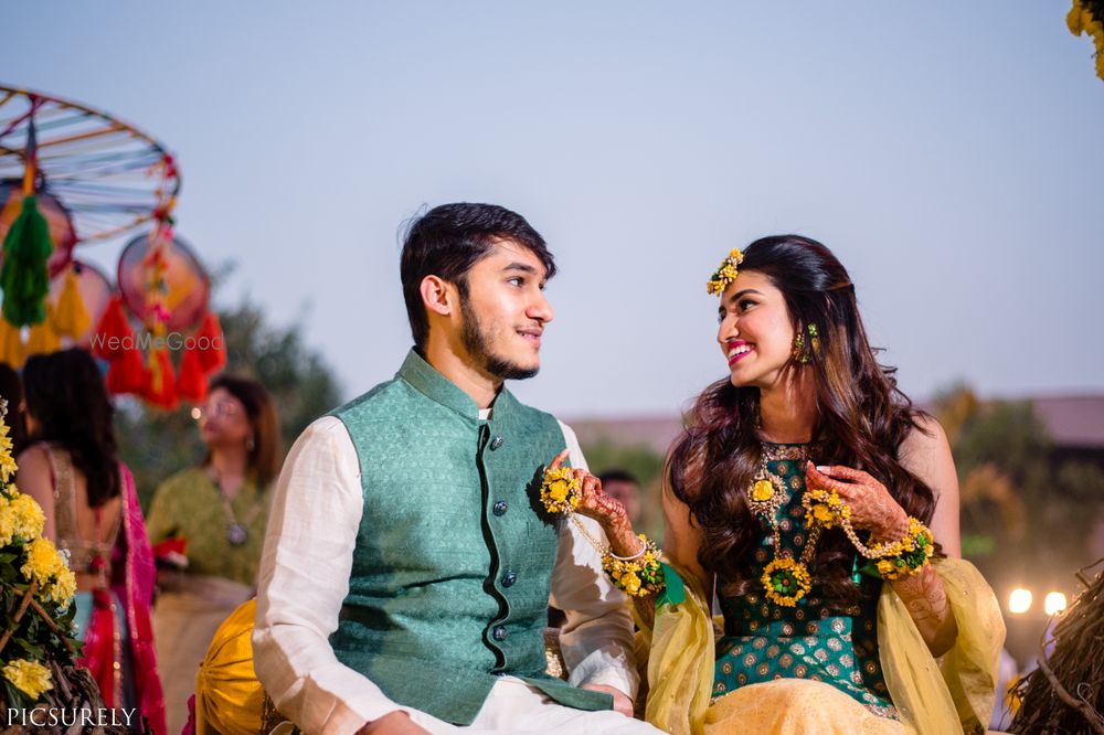 Photo of Matching bride and groom couple shot on mehendi wearing dark green