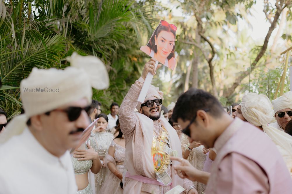 Photo of Super fun groom entry with bride's photos as a prop for the baraat