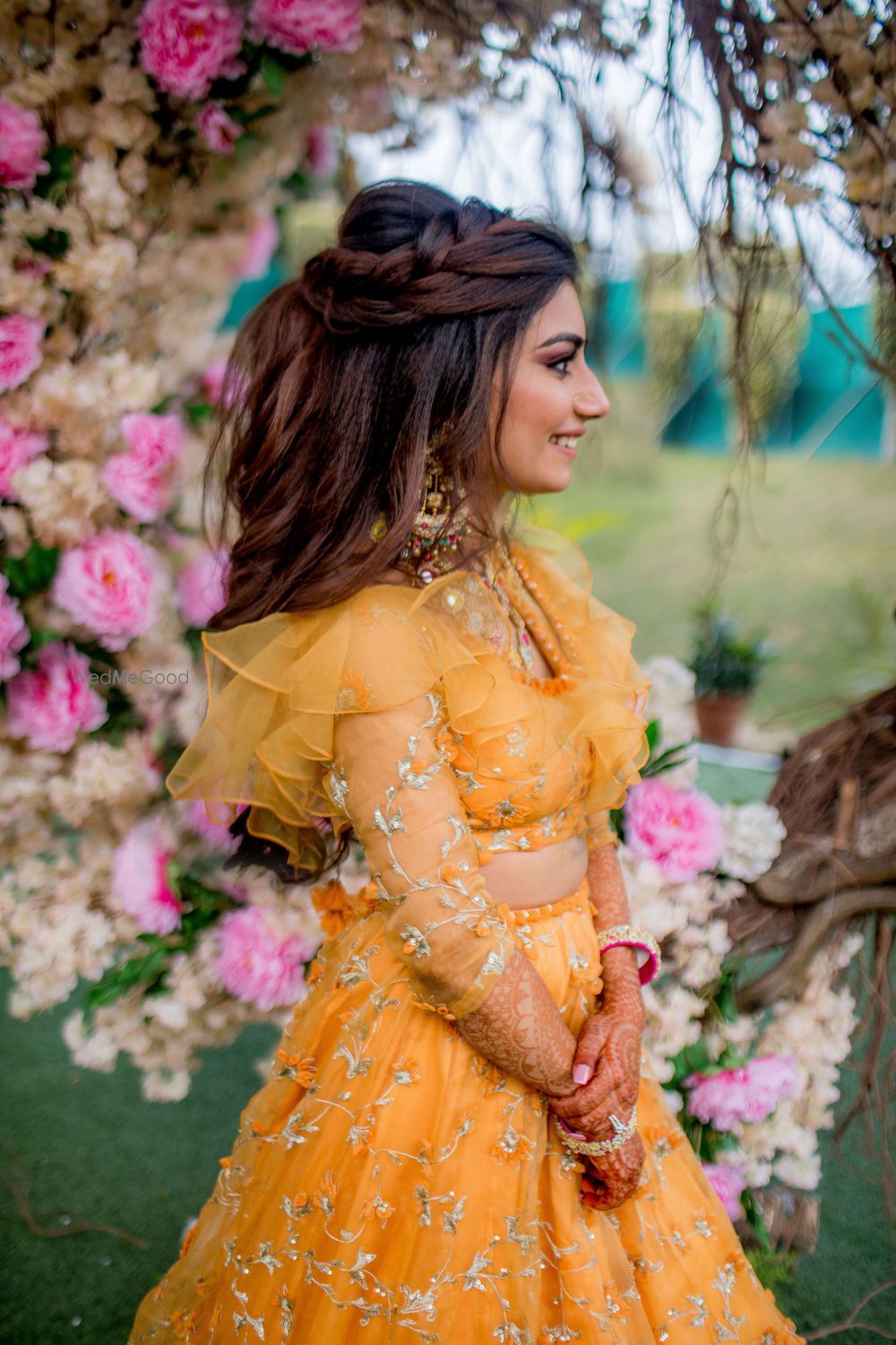 Photo of Open hair braided mehendi hairdo with yellow lehenga