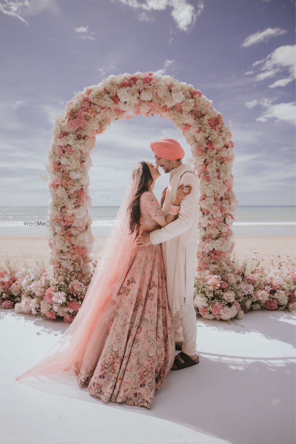 Photo of Lovely candid capture of the couple in front of a floral archway in all pastel