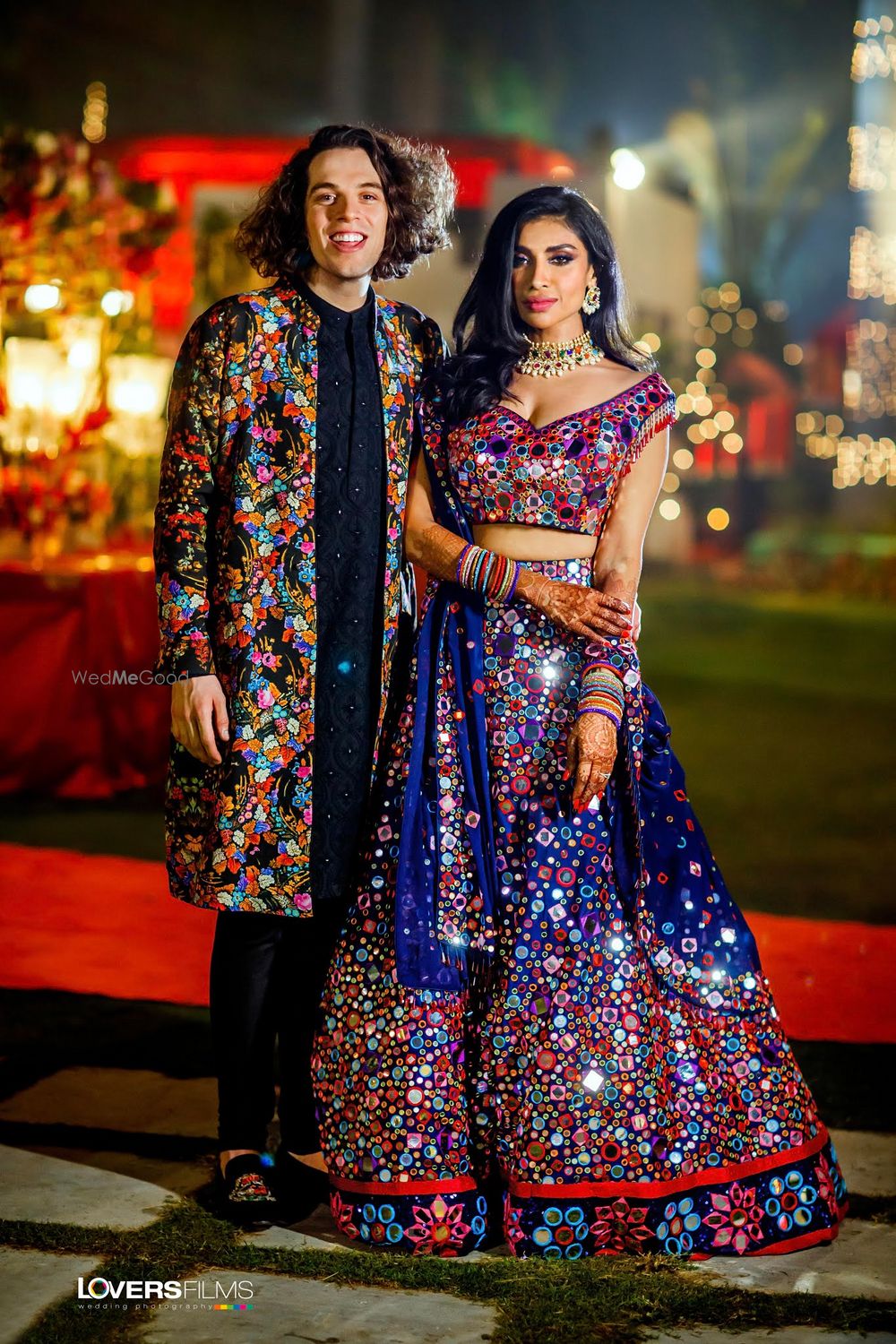 Photo of bride and groom twinning in mirror work outfits