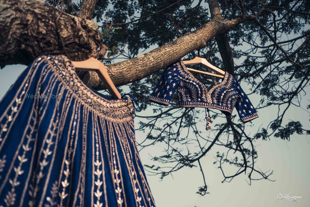 Photo of Dark blue lehenga and blouse on hanger hanging on tree