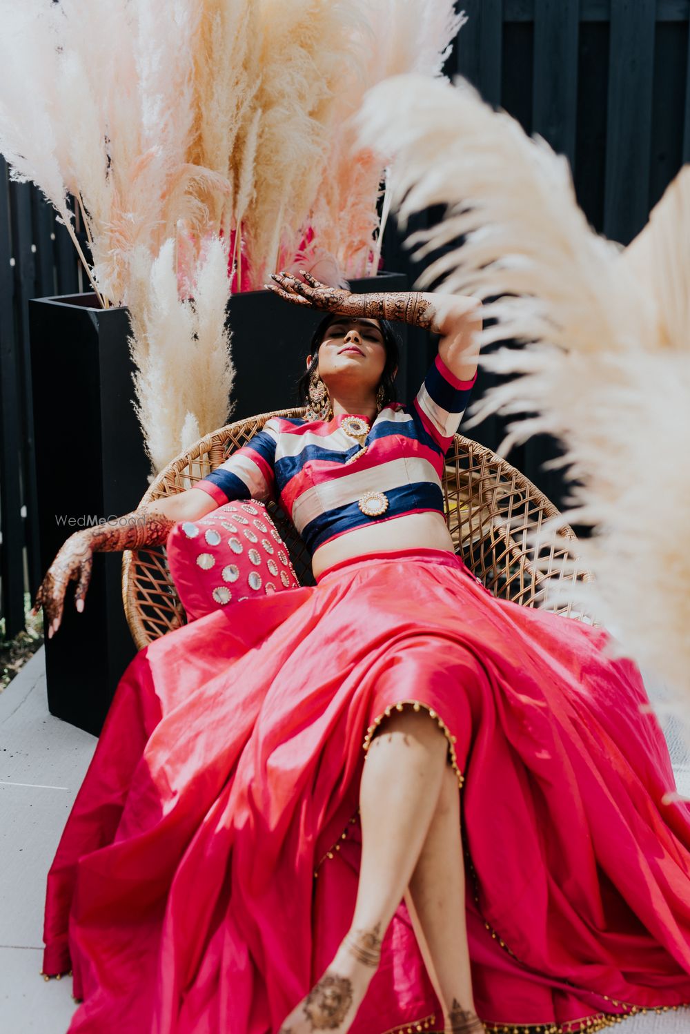 Photo of Bride wearing a crop top and lehenga set on her mehendi.