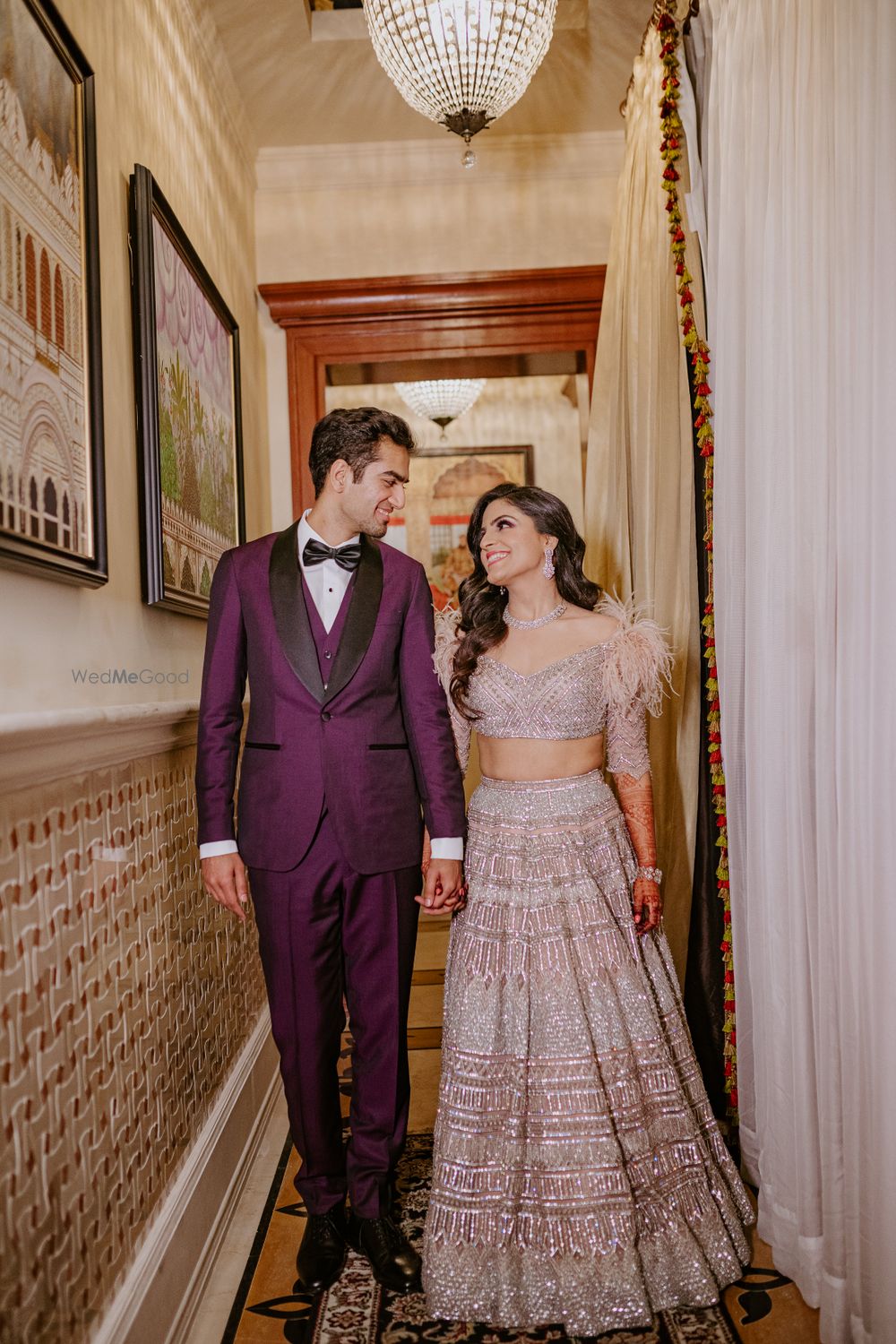 Photo of Bride and groom walking hand in hand and looking at each other.