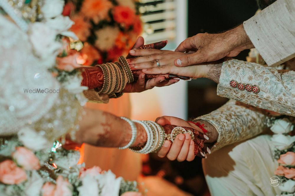 Photo of couple hand shot at mandap with parents