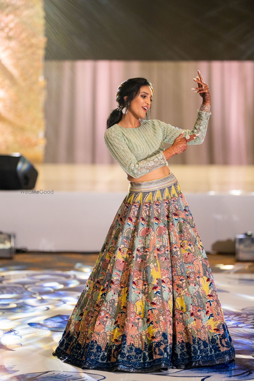 Photo of dancing bride wearing a sage green modern lehenga