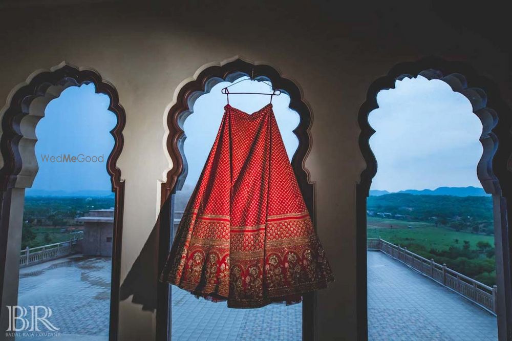 Photo of Bridal red sabysachi lehenga on hanger sunset shot