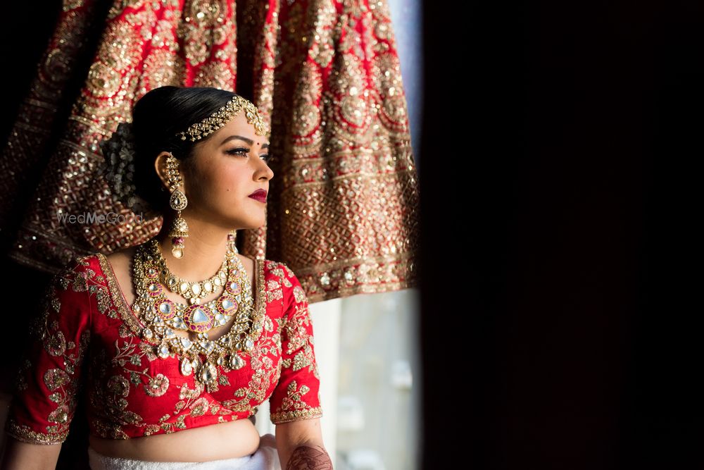 Photo of Getting ready bridal portrait with lehenga in backdrop