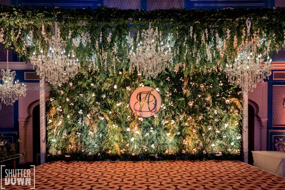 Photo of Sangeet stage decor with green backdrop and chandeliers