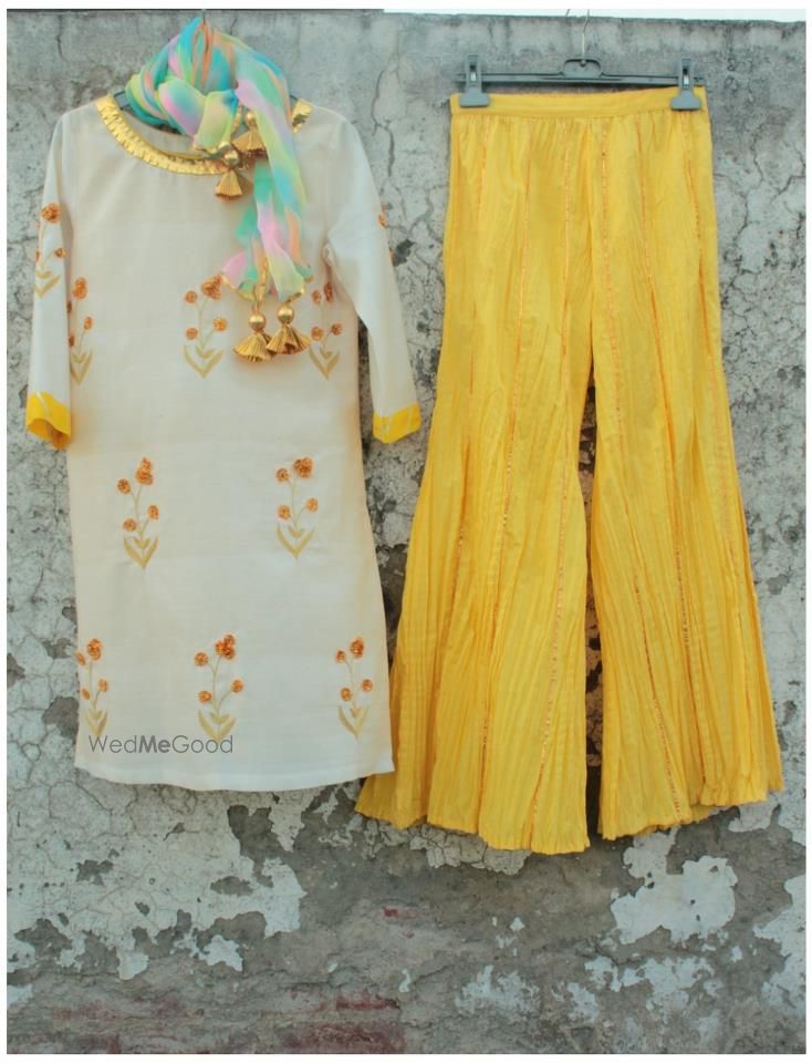 Photo of wide legged pallazo pants in yellow with white kurta and gota work. tie dye dupatta