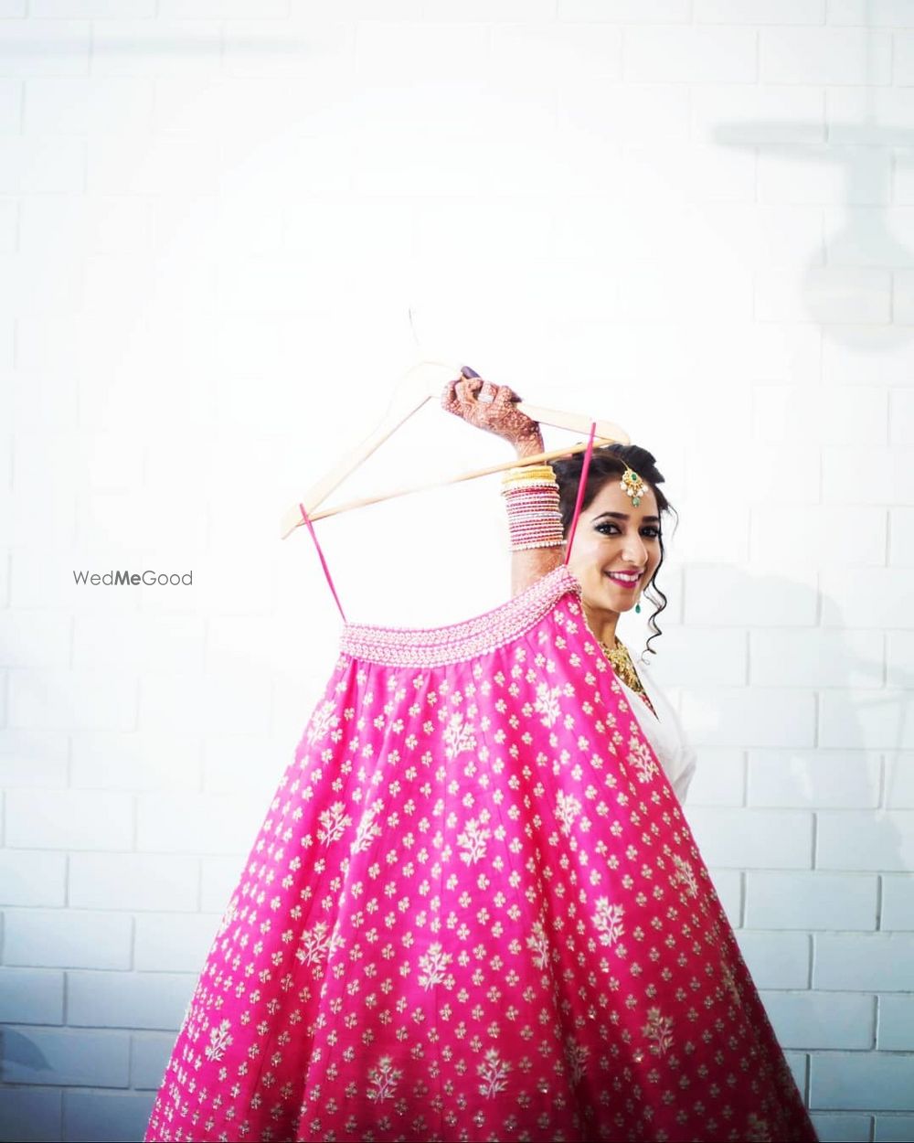 Photo of bride getting ready shot holding up her pink lehenga