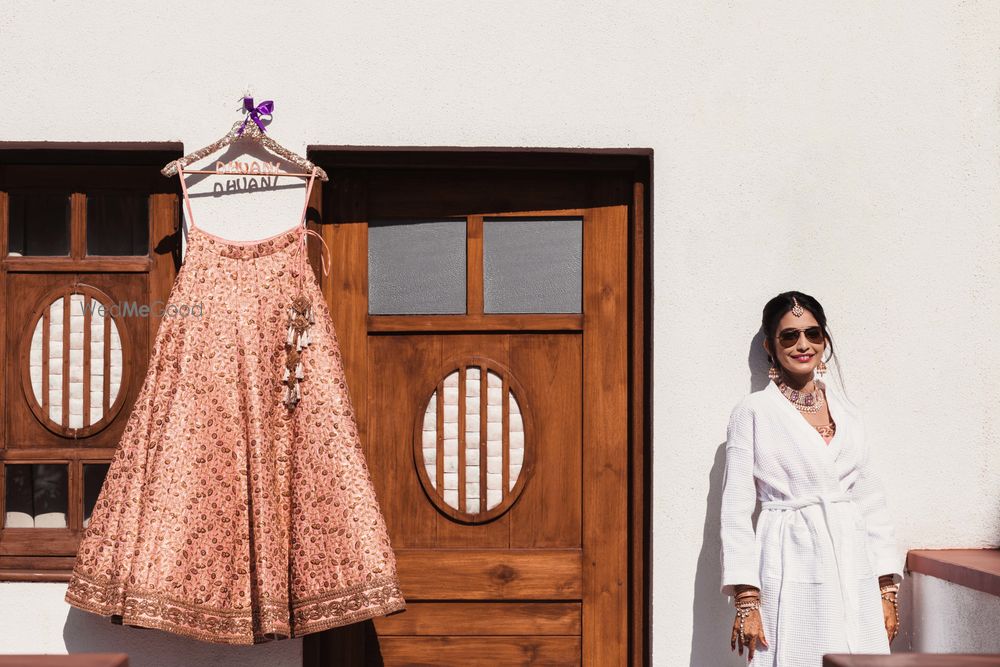 Photo of Bride getting ready shot in robe with lehenga on hanger