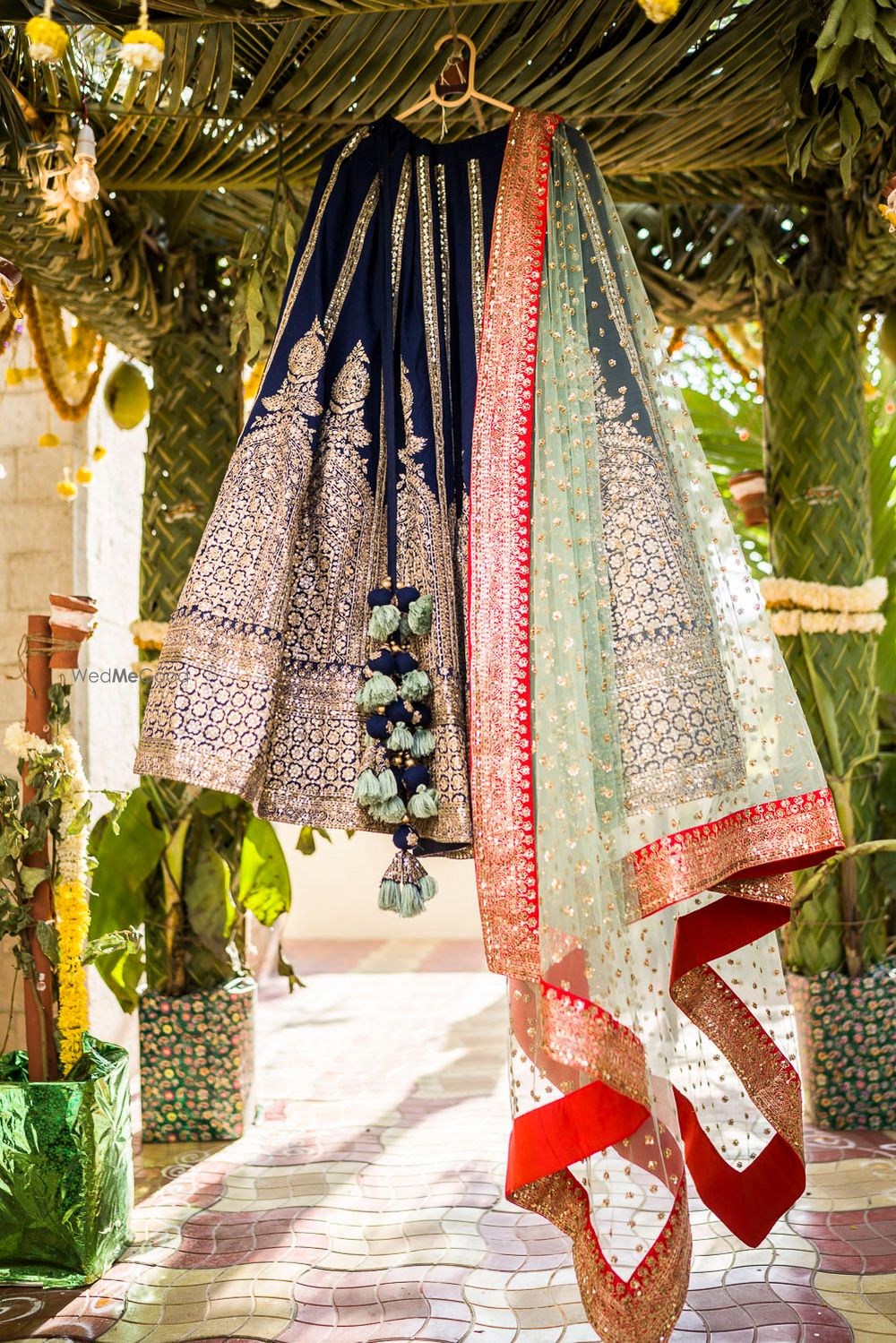 Photo of Black and green lehenga for sangeet on hanger with orange border