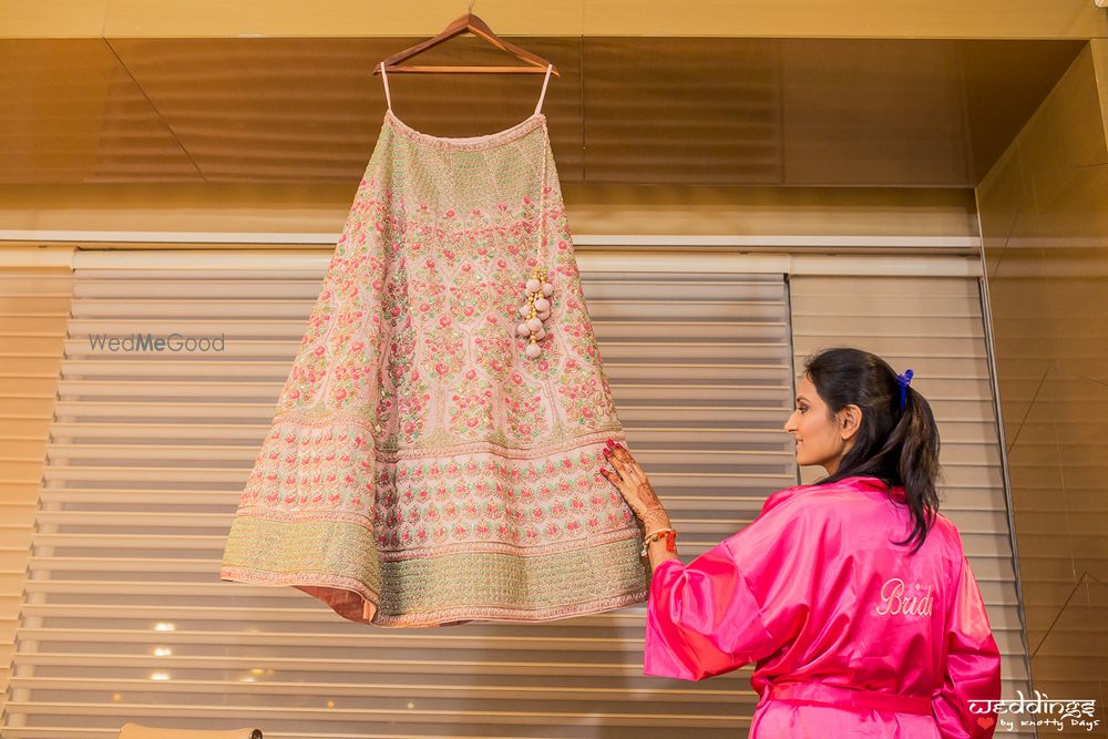 Photo of Getting ready shot idea with lehenga on hanger and bride in robe