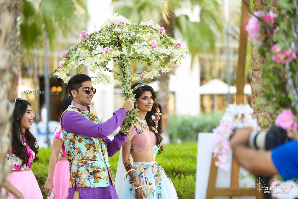 Photo of Couple entering floral umbrella on mehendi