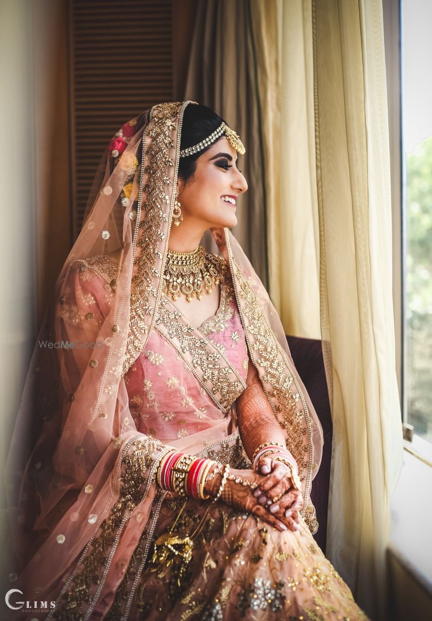 Photo of A bride in an onion pink and gold lehenga on her wedding day