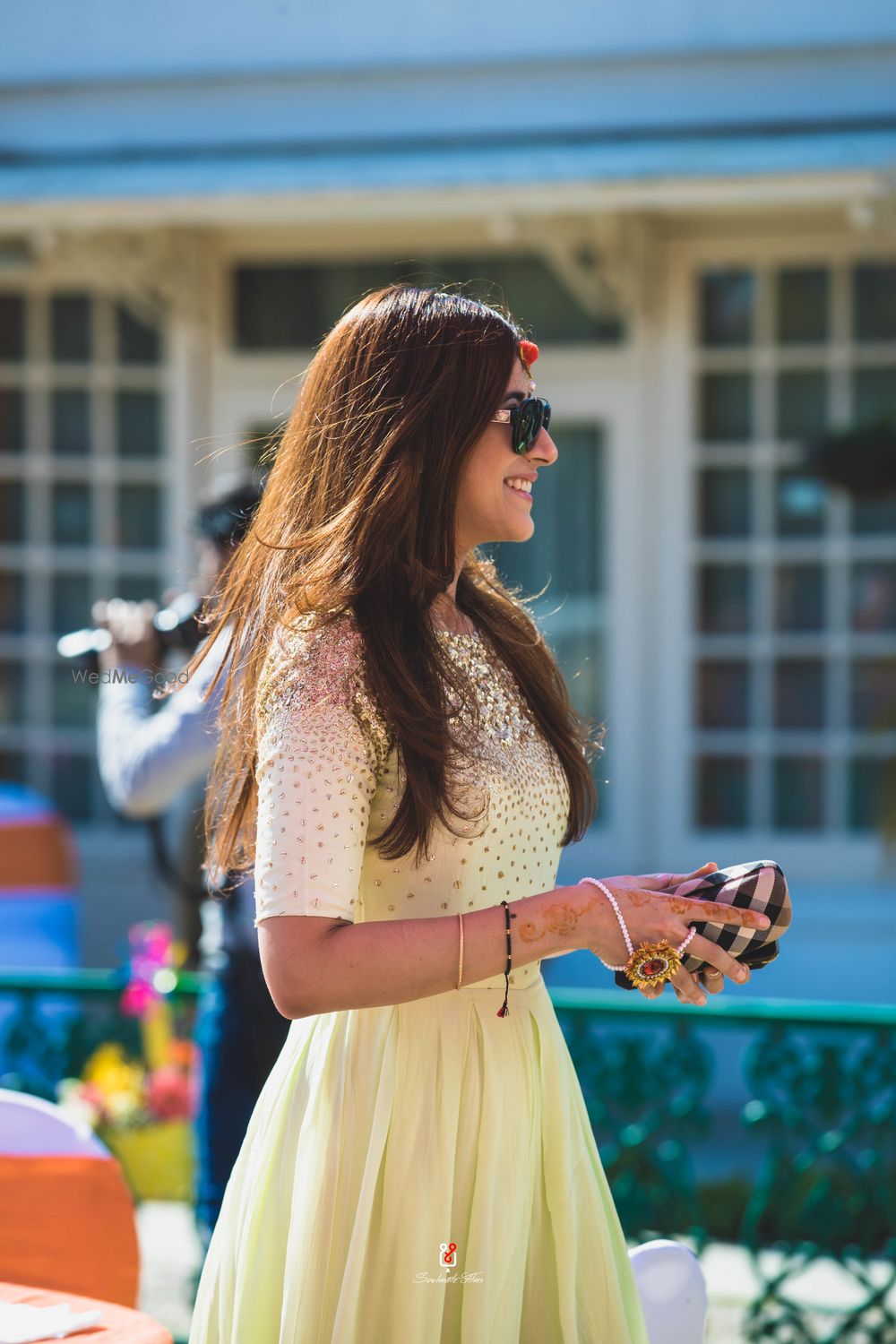 Photo of A portrait clicked of the sister of the bride in a yellow outfit and wearing sunglasses