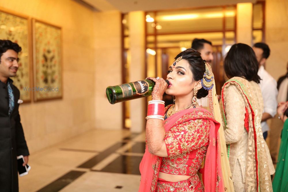 Photo of Bride in Red Posing with Whiskey Bottle