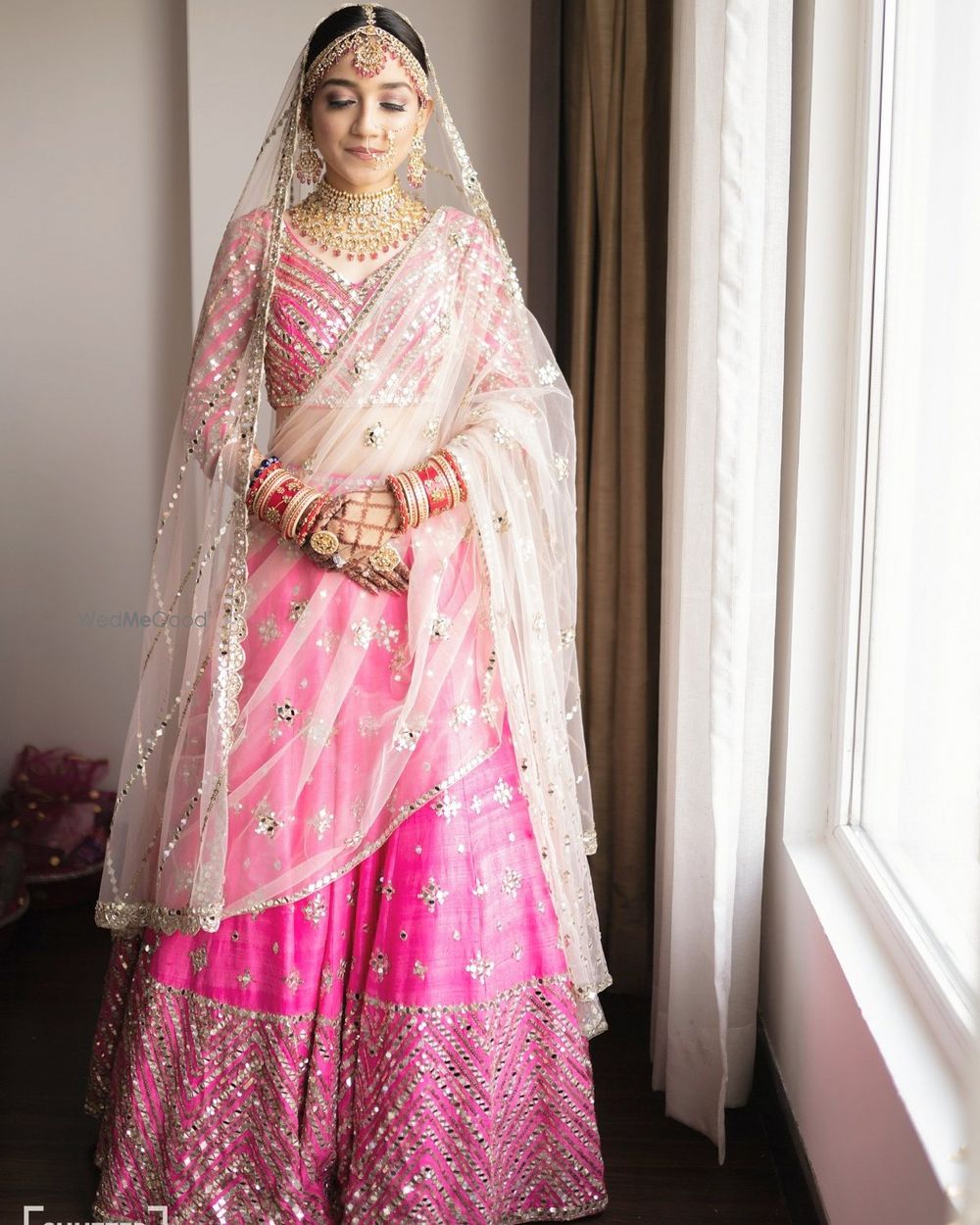 Photo of Bride wearing a bright pink lehenga with a white dupatta.