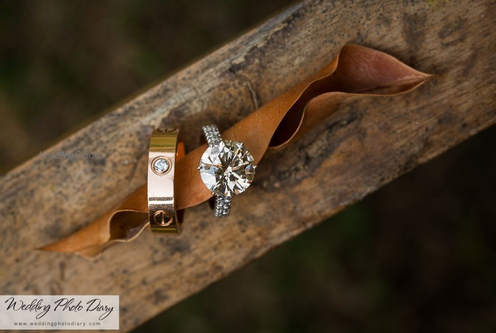 Photo of His and Her Solitaire Engagement Rings on Log