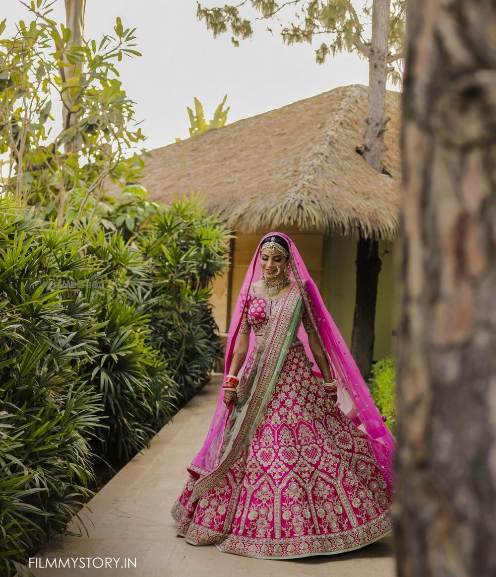 Photo of twirling bride in bright pink lehenga with green dupatta