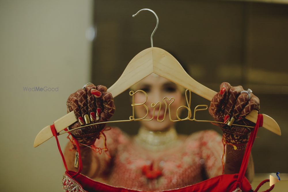 Photo of bride holding up a bride hanger with lehenga