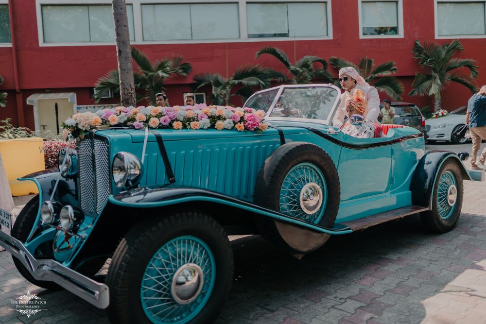 Photo of Groom entry on a vintage car.