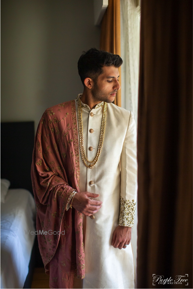 Photo of Groom wearing an ivory sherwani with a dusty pink stole.