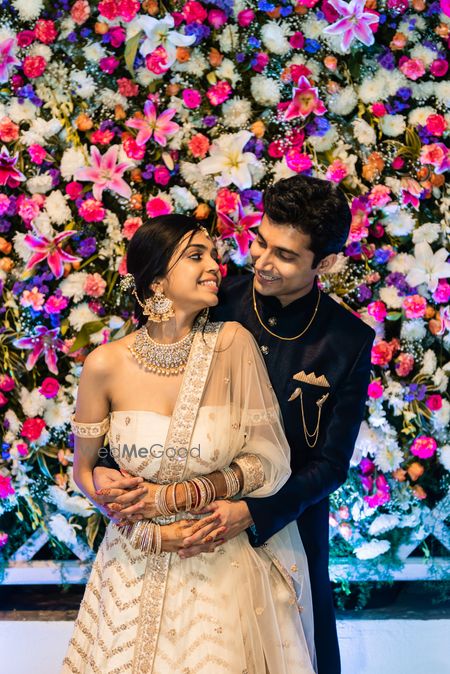 Photo of A couple poses infront of a floral wall on their engagement