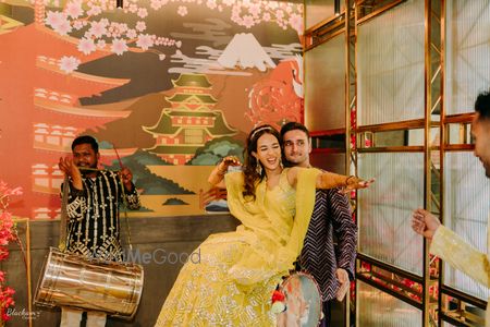 Photo of bride and groom having fun with dhol at mehendi