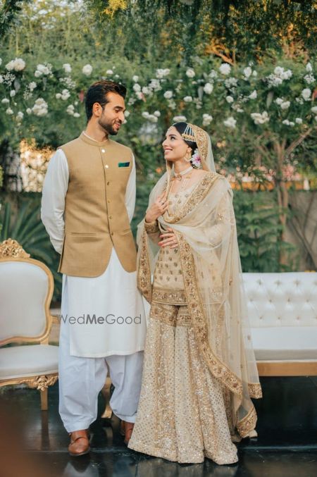 Photo of Candid couple portrait of a bride and groom dressed in white and gold.