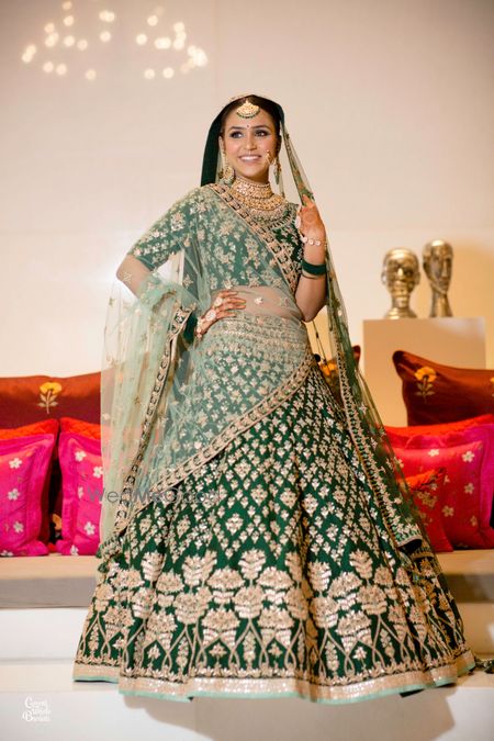 Photo of A bride in green and gold lehenga for her wedding