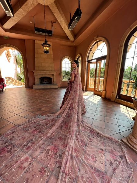 Photo of bride in maroon lehenga with light pink contrasting dupatta as a long train