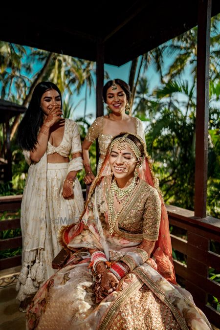 Photo of bright and happy bride shot with her bridesmaids while getting ready