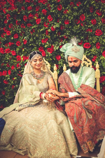 Photo of A couple in coordinated mint green outfits at the mandap