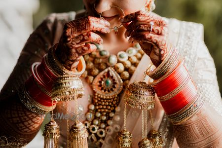 Photo of Bride putting on Nath in a full bridal ensemble