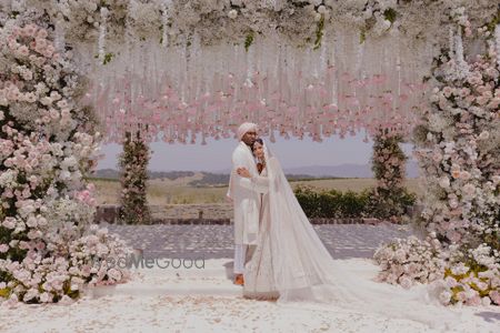 Photo of Lovely all-white themed outdoor wedding portrait with the couple in coordinated outfits