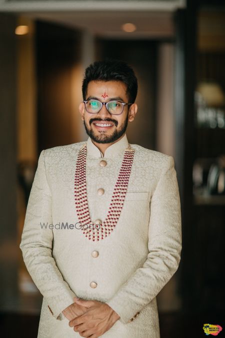 Photo of Groom in off white sherwani and contrasting necklace