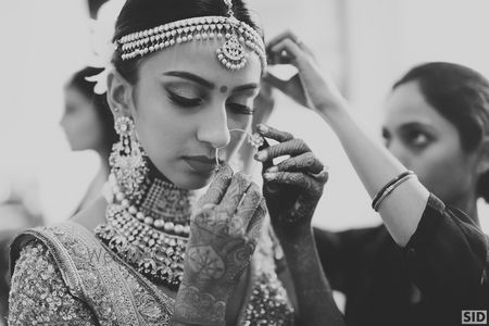 Photo of Bride adjusting nath