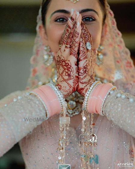 Photo of Stunning close up bridal shot with a oval shaped solitaire engagement ring and baby pink chooda