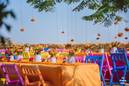 Photo of colourful mehndi table decor idea with pickle jars and flowers