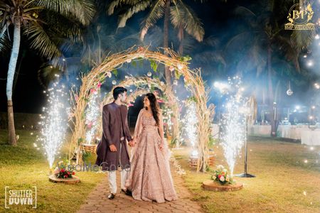 Photo of couple walking through entrance arch and sparklers on the side