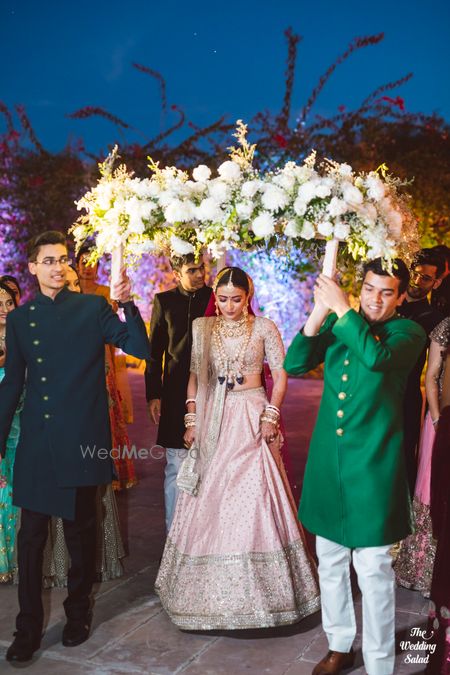 Photo of bride in pastel lehenga making her entry under a white phoolon ka chadar