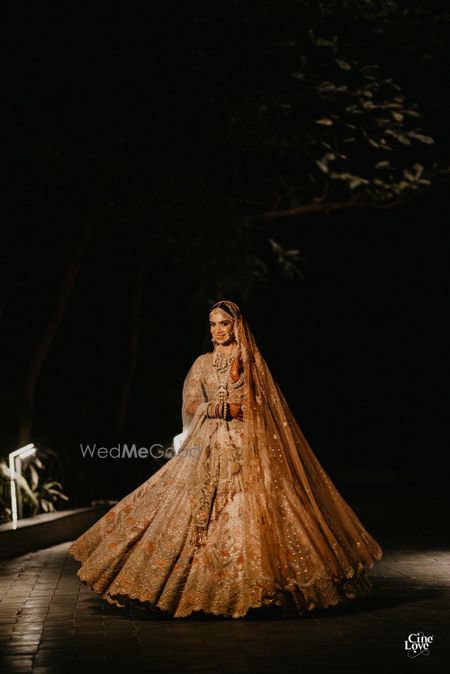 Photo of Bride twirling in a dull gold lehenga