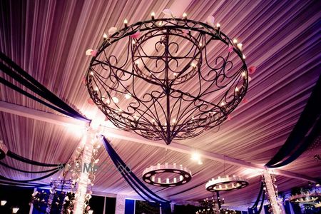 Photo of glamorous ceiling decor with wrought iron chandeliers and candles