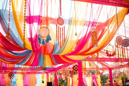 Photo of Mehendi decor idea with dreamcatchers hanging on tent drapes